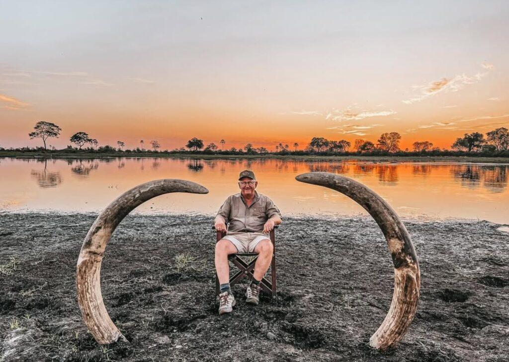 Hunter seated between elephant tusks after a Botswana safari