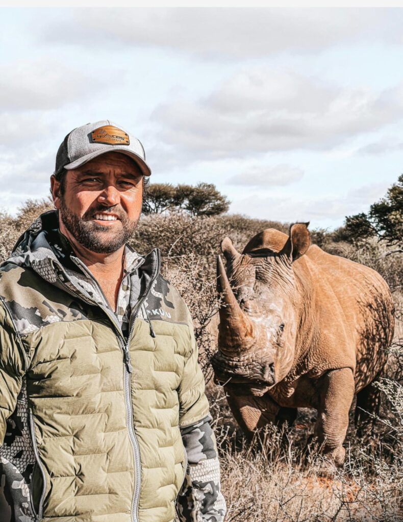 Safari guide standing near a rhinoceros in African bushland
